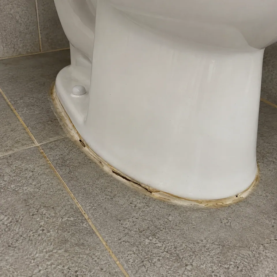 변기 밑동과 바닥 타일 사이 누렇게 변하고 틈이 벌어진 실리콘 줄