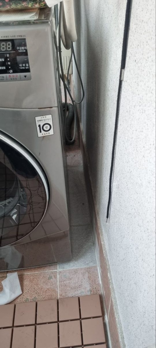 세탁기와 벽 사이 좁은 틈으로 가는 확인선을 내려 가려진 배관 구간을 살피는 현장 사진