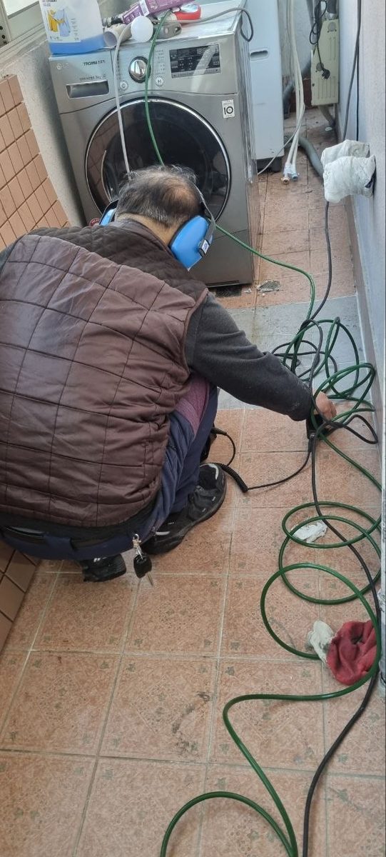 바닥에 앉아 청음 센서를 배관 위치에 대고 구간별로 반복 비교하며 누수 지점을 좁히는 현장 사진